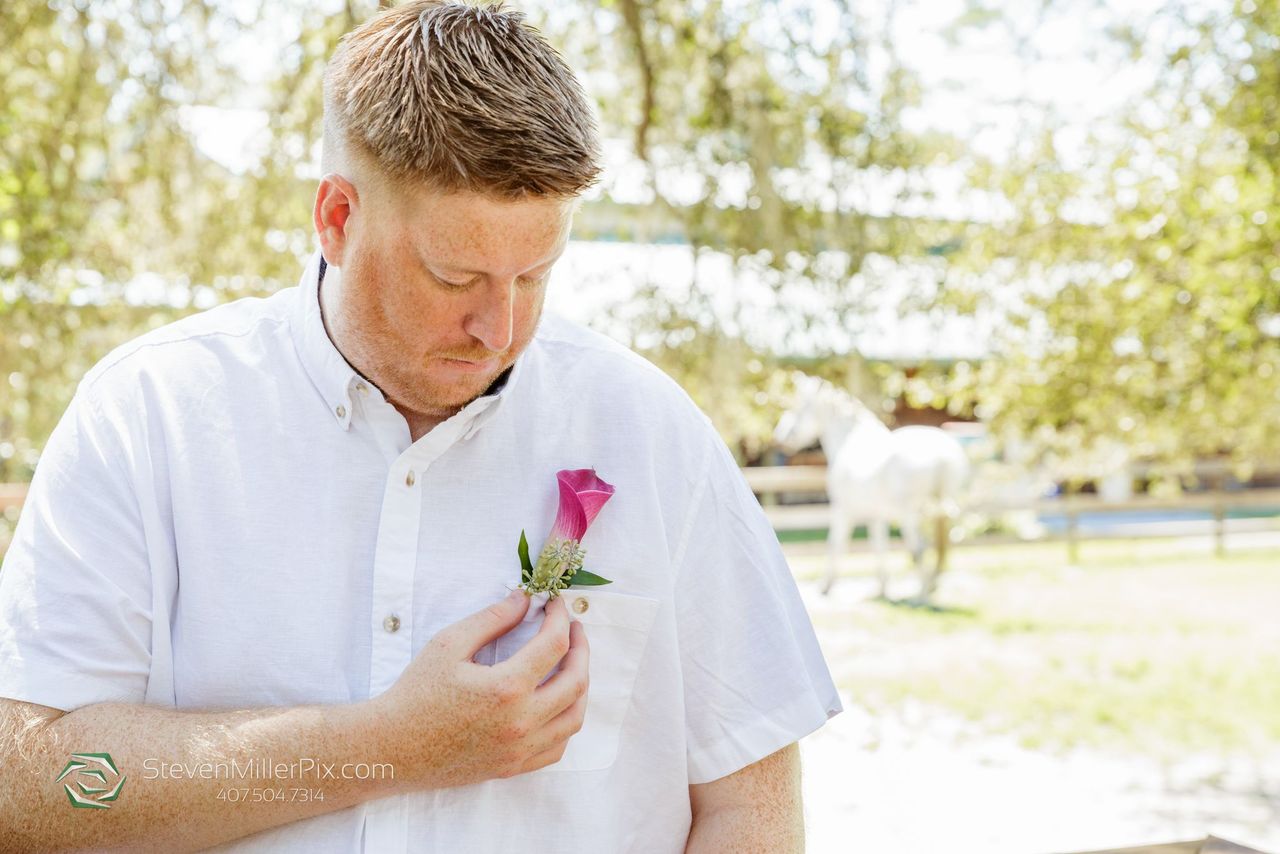 the-groom-placing-his-pink-floral-boutonniere 