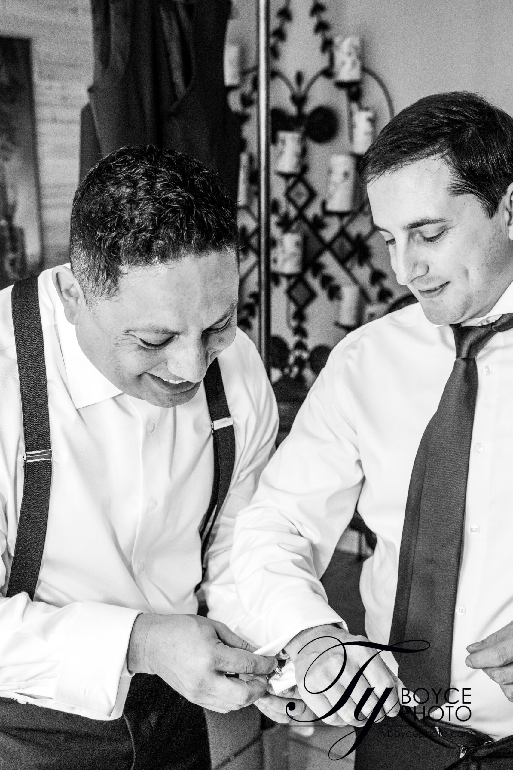 Two grooms helping each other with their cufflinks