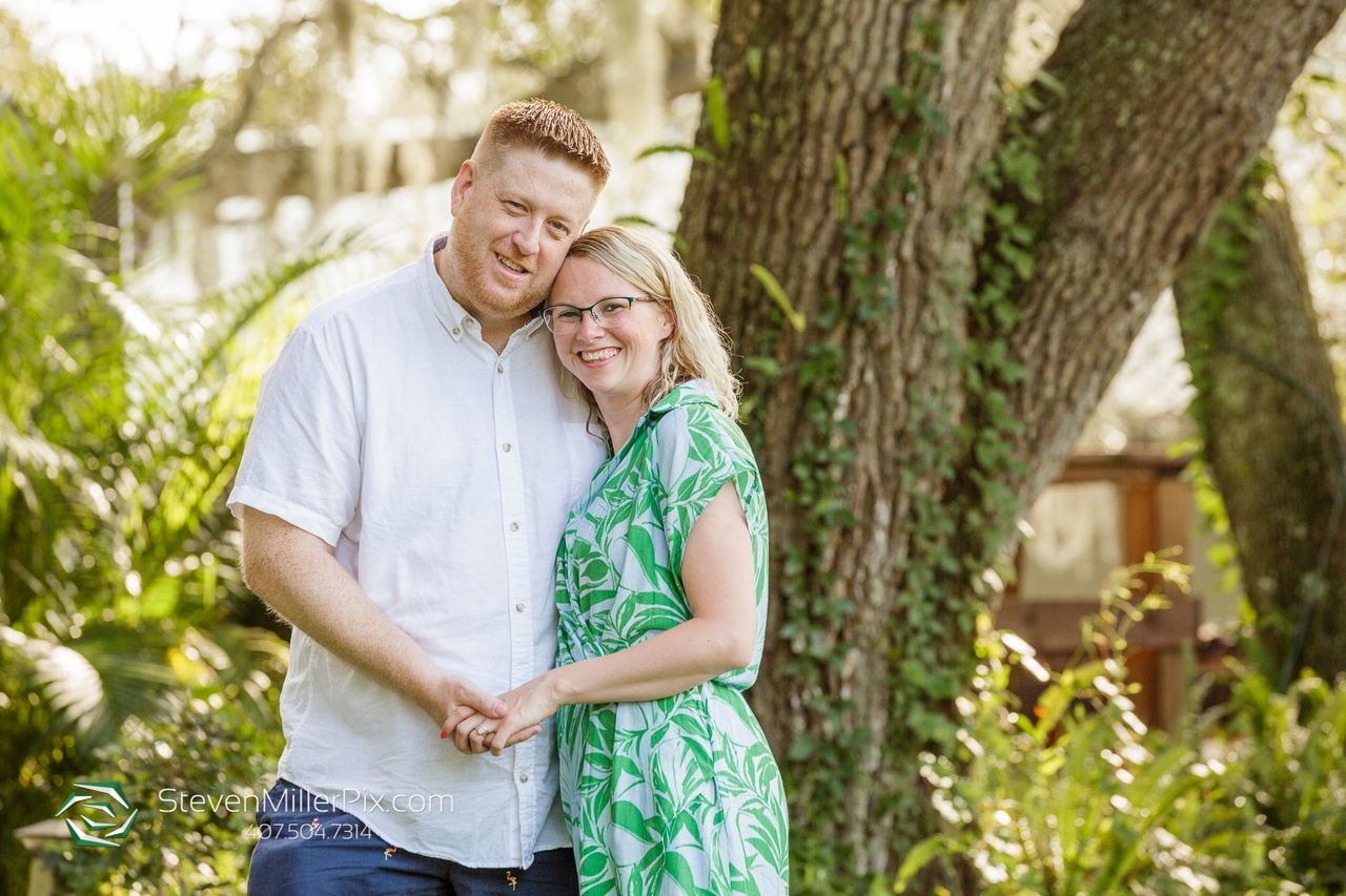 A couple embracing each other in front of a large tree while posing for a portrait at their Memorable Anniversary Shoot