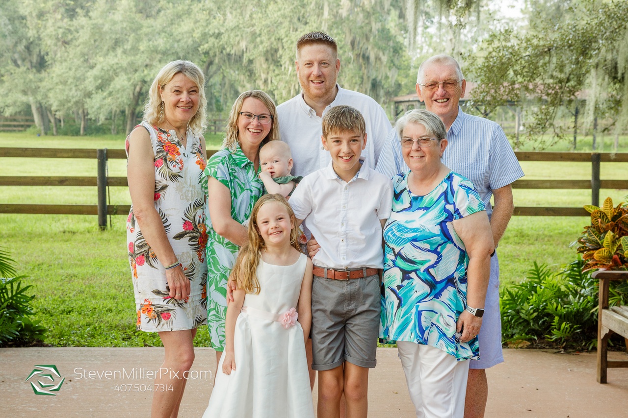 The returning couple with their kids and family members posing for a picture with gorgeous greenery in the background