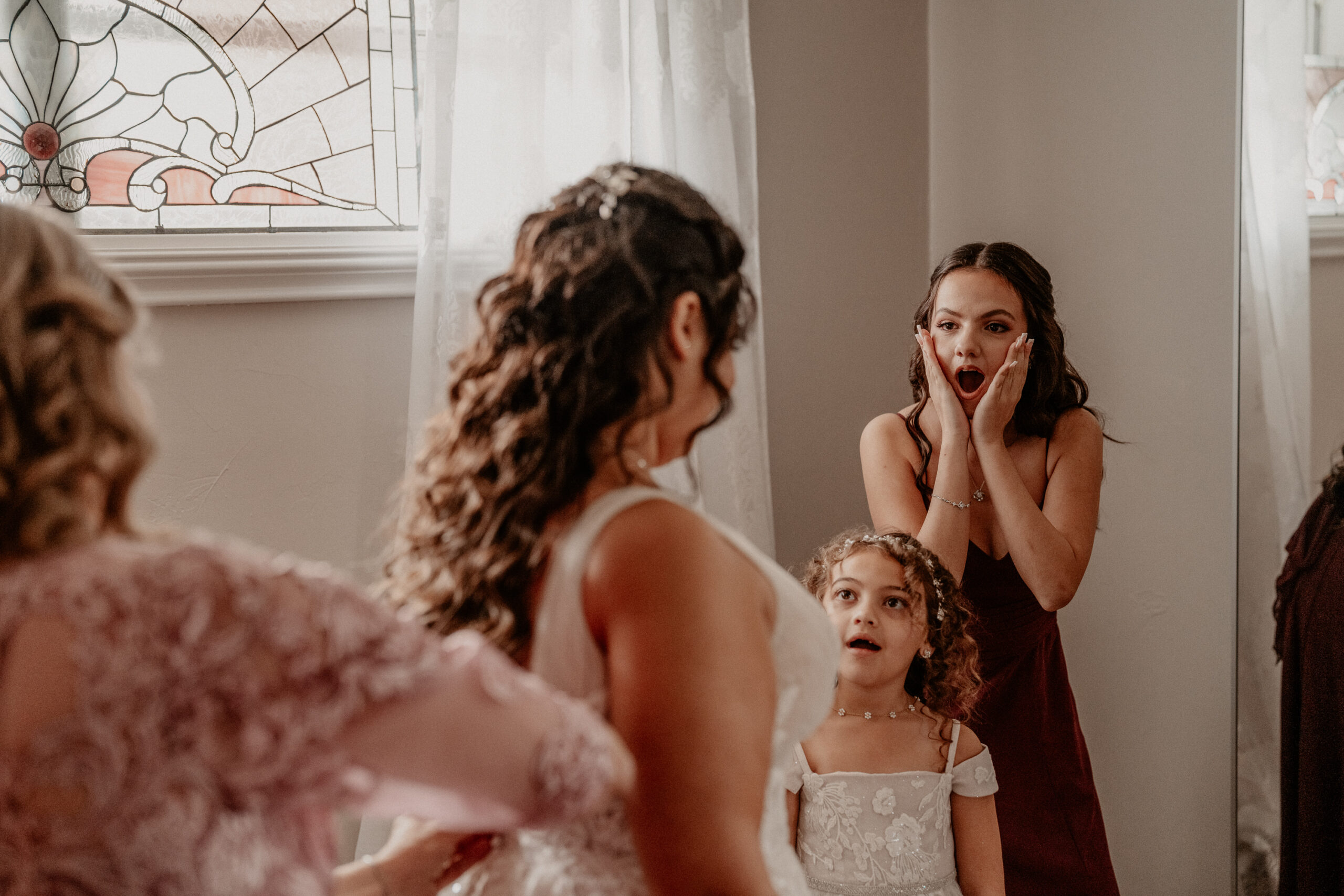 Two little girls with shocked faces getting a glimpse of the bride for the first time