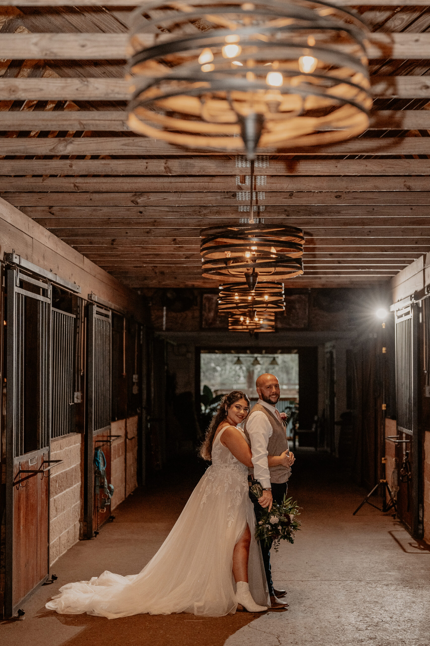 Bride and groom in the barn with a beautiful circular chandelier hanging down